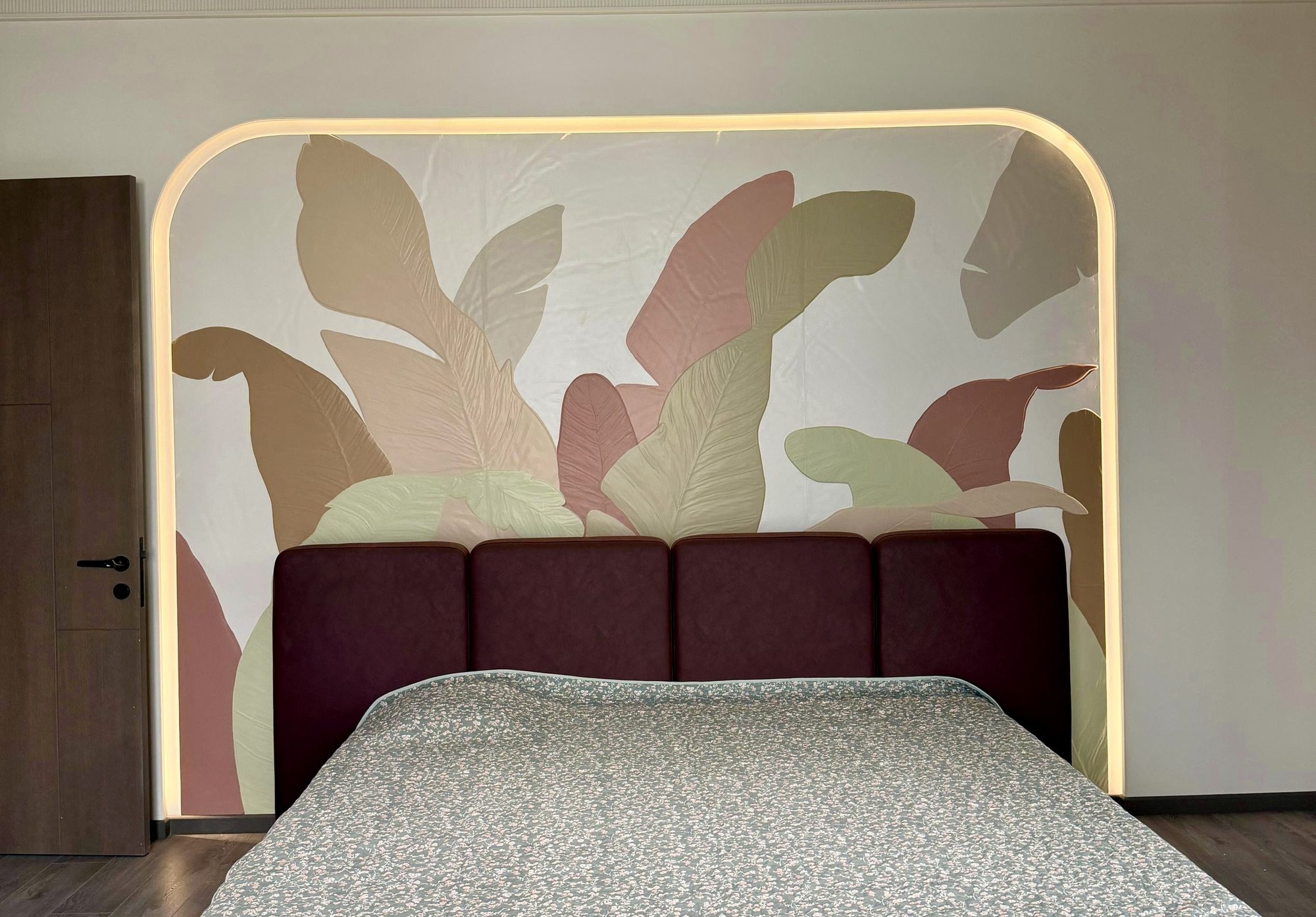 Soft-toned abstract leaf mural behind a bed