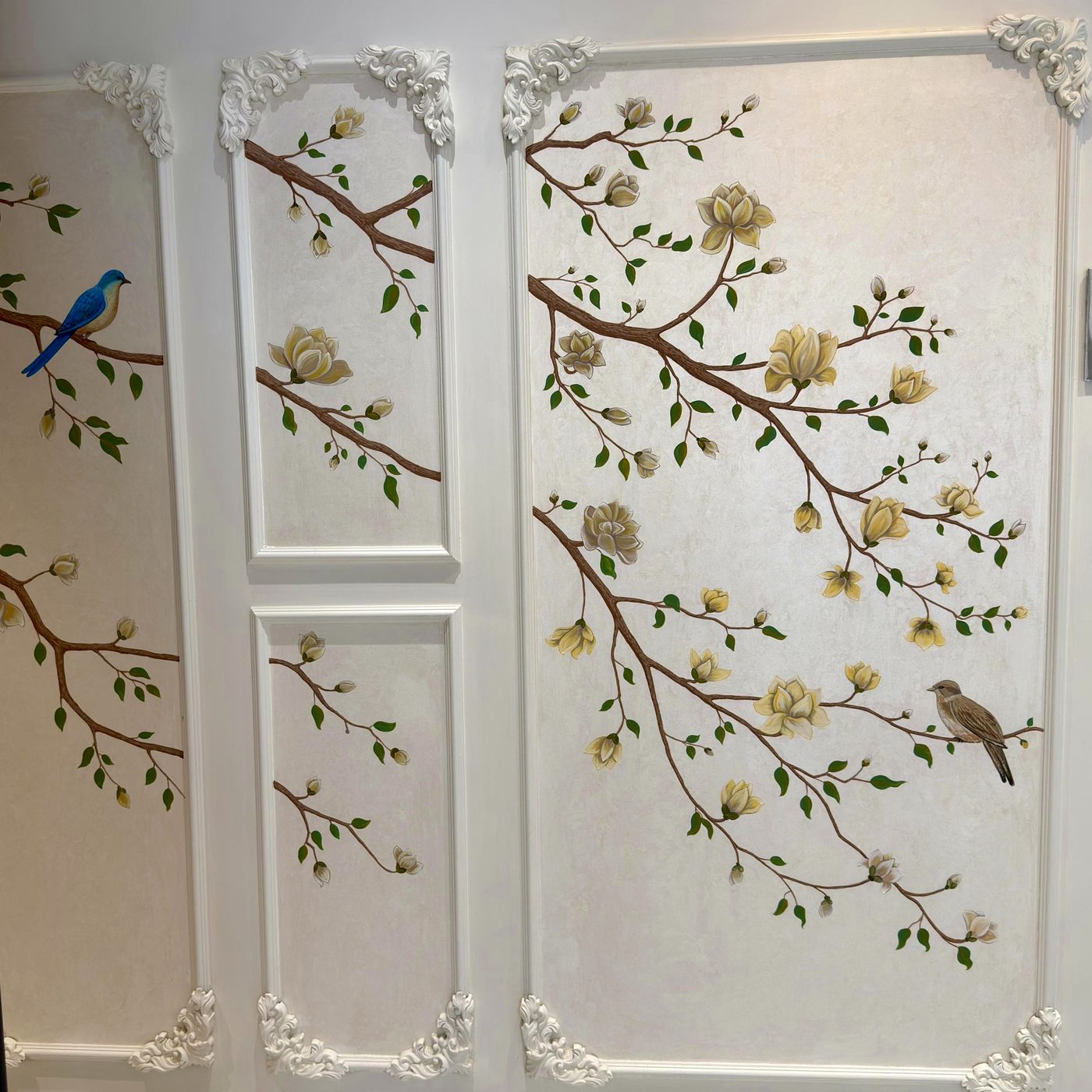 Painted branches, blossoms and birds across panelled walls